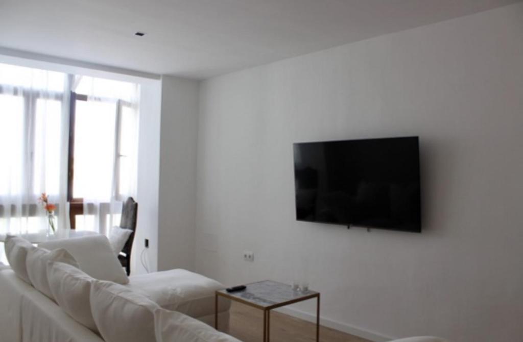 sala de estar con sofá blanco y TV de pantalla plana en PLAZA CABILDO 4, en Sanlúcar de Barrameda