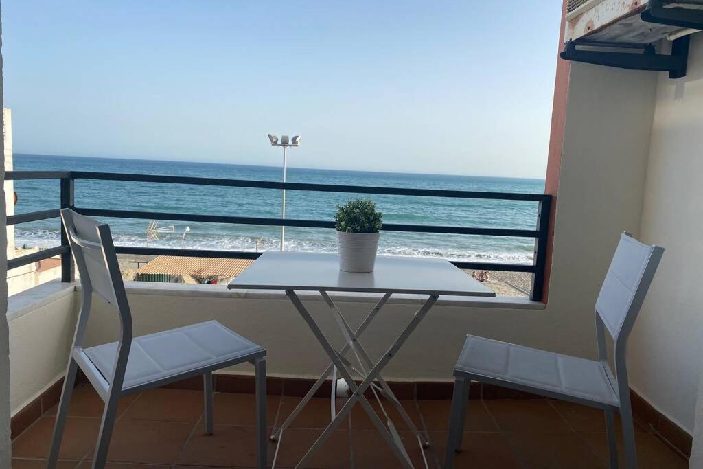 una mesa y sillas en un balcón con vistas al océano en Maravilloso apartamento en primera linea de playa con vistas al mar en Caleta de Vélez 2 D en Caleta De Velez