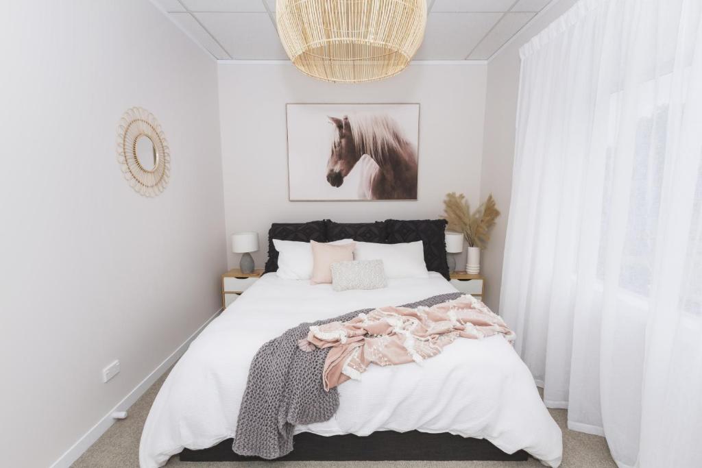 1 dormitorio con 1 cama con una foto de caballo en la pared en Rustling Oaks NZ Boho Pool House, en Cambridge