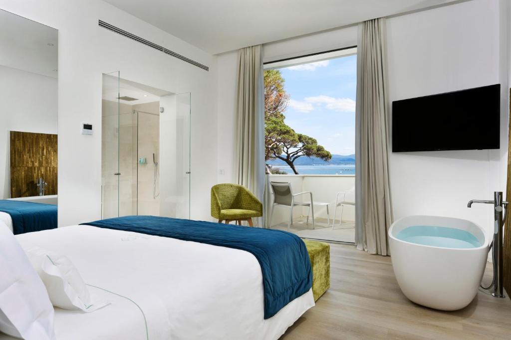 una camera d'albergo con un grande letto e una vasca di The Sense Experience Resort a Follonica