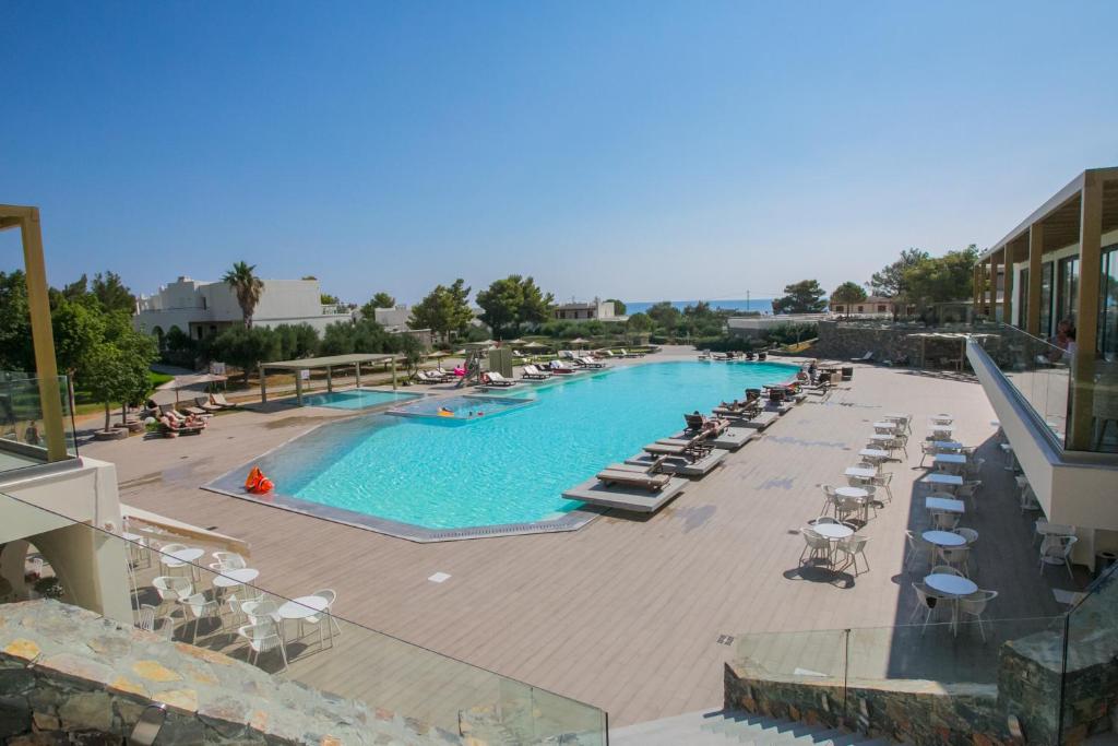 een zwembad met ligstoelen en een resort bij Almyra Hotel & Village in Koutsounari