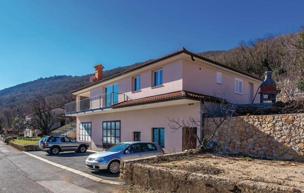 a house with two cars parked in front of it at Apartment Martina in Brseč