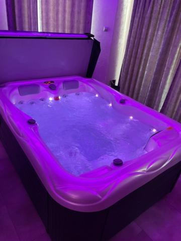 uma banheira de hidromassagem num quarto com iluminação roxa em New York Pension em Dunajská Streda