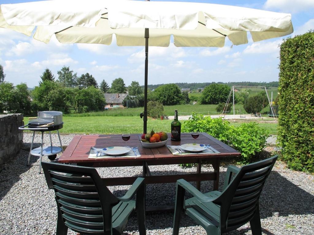 einen Tisch mit einem Sonnenschirm und einer Flasche Wein in der Unterkunft Appartement idéal près de Durbuy / Ideaal appartement nabij Durbuy / Ideal apartment near Durbuy in Hotton