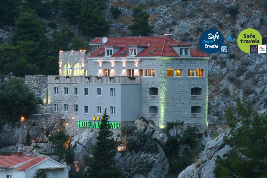 un edificio en una montaña con un cartel en él en Hotel Villa Dvor, en Omiš
