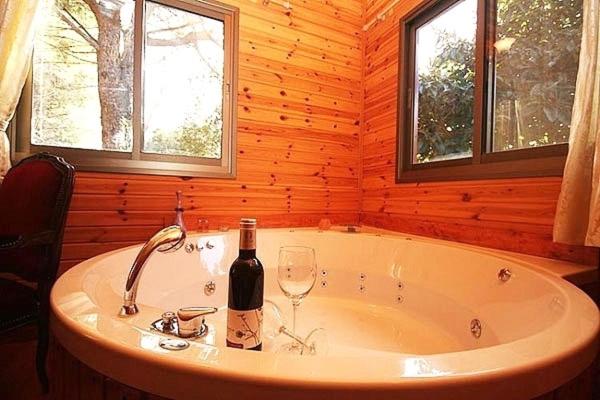 a bath tub with a bottle of wine and a wine glass at Amirim Atmosphere in Amirim
