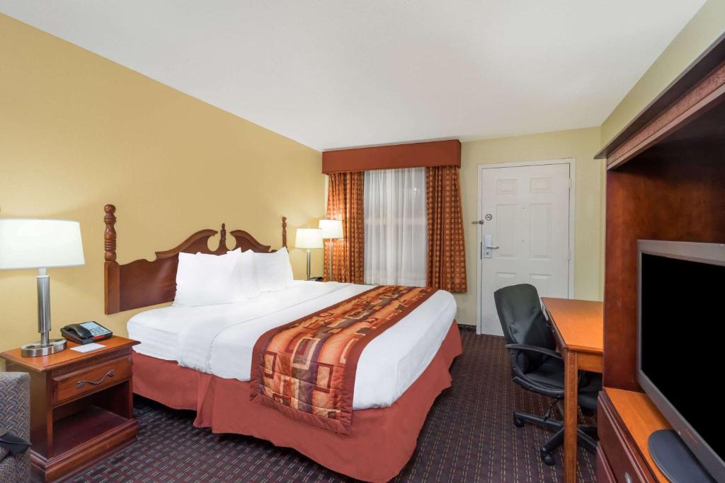 um quarto de hotel com uma cama, uma secretária e uma televisão em Baymont by Wyndham Goodlettsville Nashville em Goodlettsville