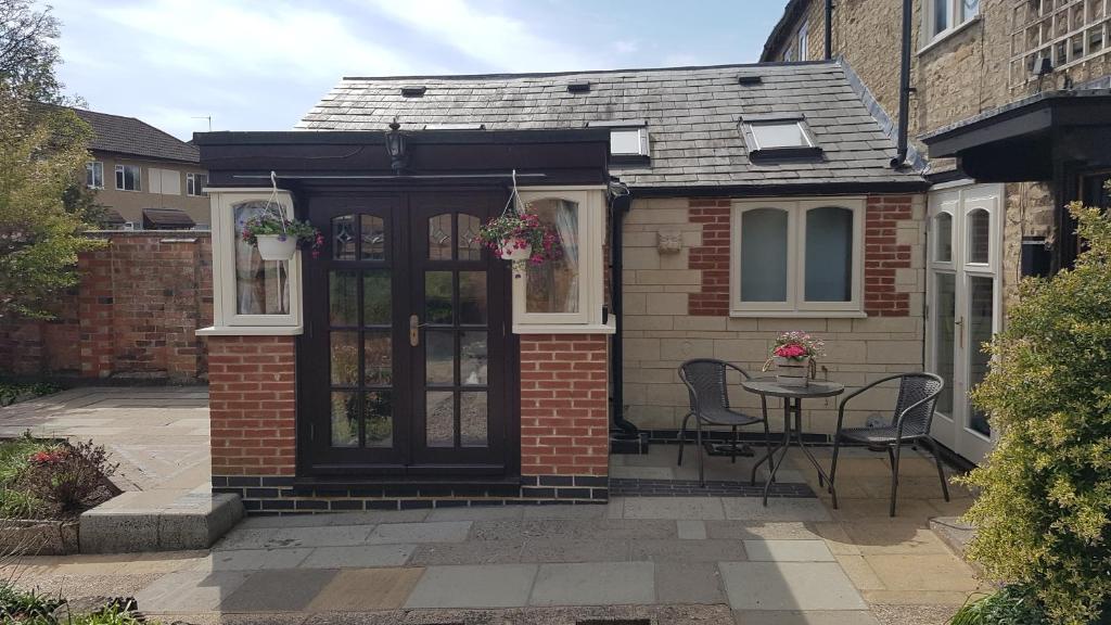 una casa de ladrillo con una puerta negra y una mesa en Ruby Cottage en Irthlingborough