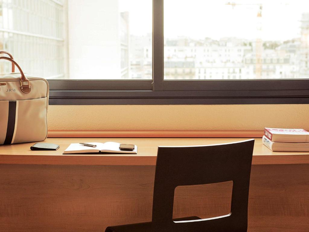 a chair sitting in front of a desk with a window at ibis London Elstree Borehamwood in Borehamwood