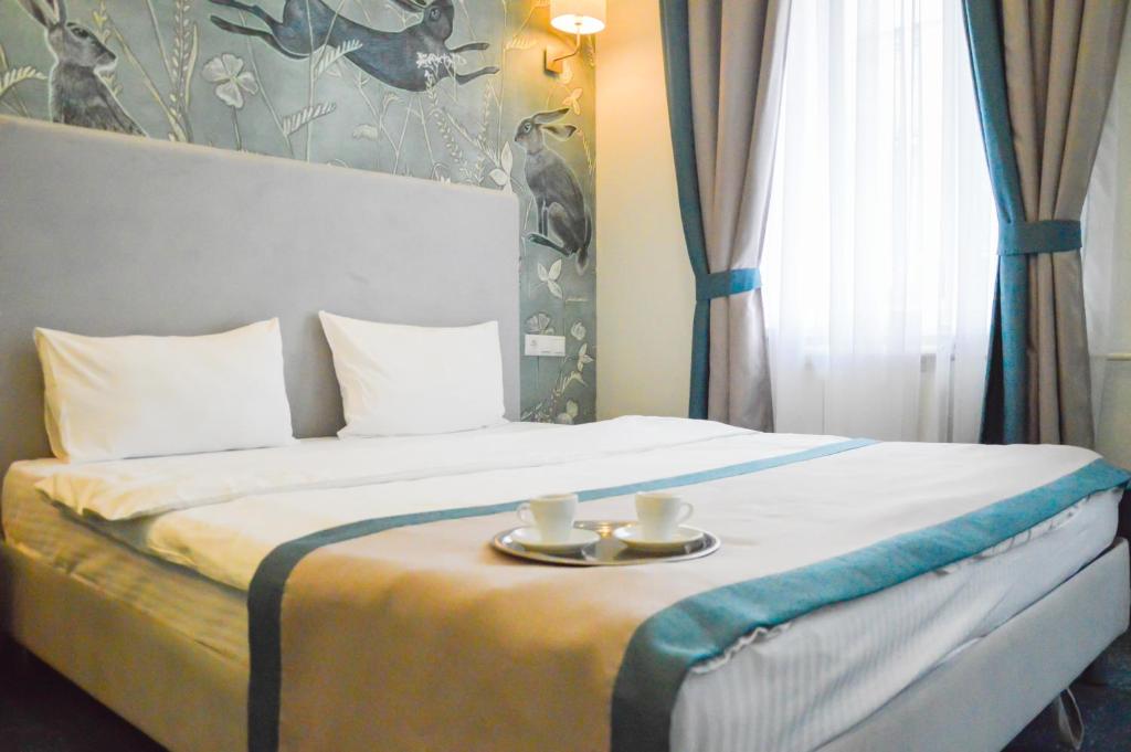 Una cama con dos tazas y una bandeja. en Kirin Hotel en Moscú