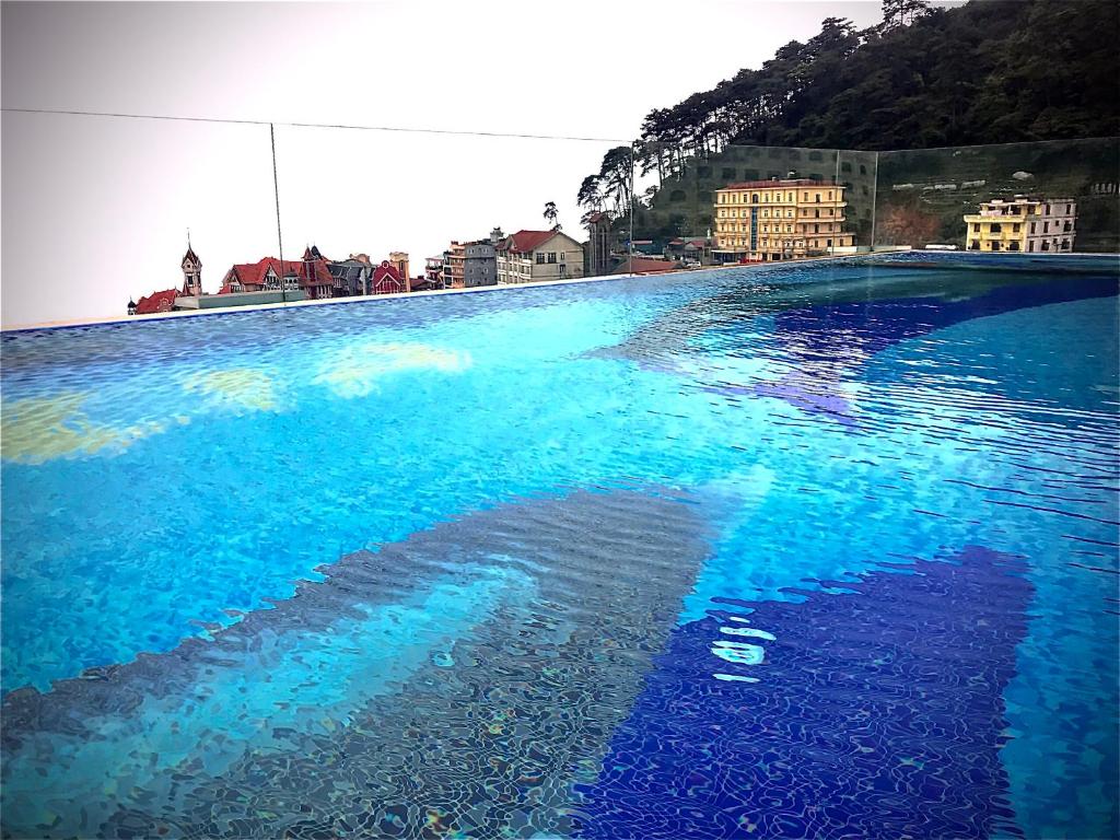 ein großer Pool mit blauem Wasser mit Gebäuden im Hintergrund in der Unterkunft Camellia Luxury Hotel Tam Đảo in Tam Ðảo