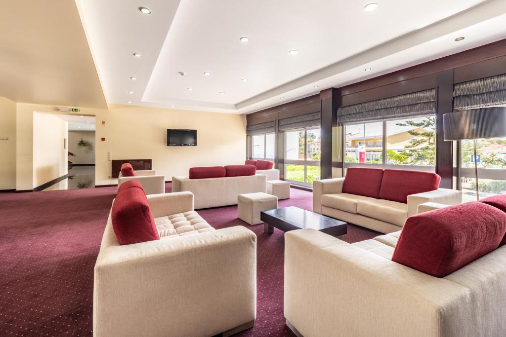 a large living room with white furniture and red pillows at Hotel Colmeia in Monte Real