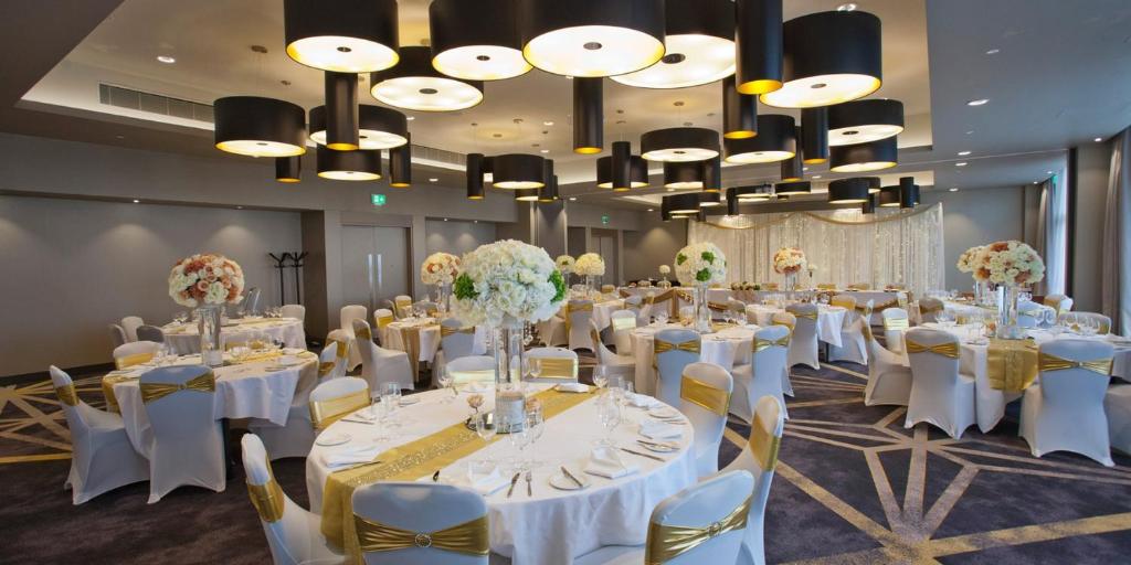 a banquet hall with white tables and chairs and chandeliers at Crowne Plaza Aberdeen Airport by IHG in Dyce