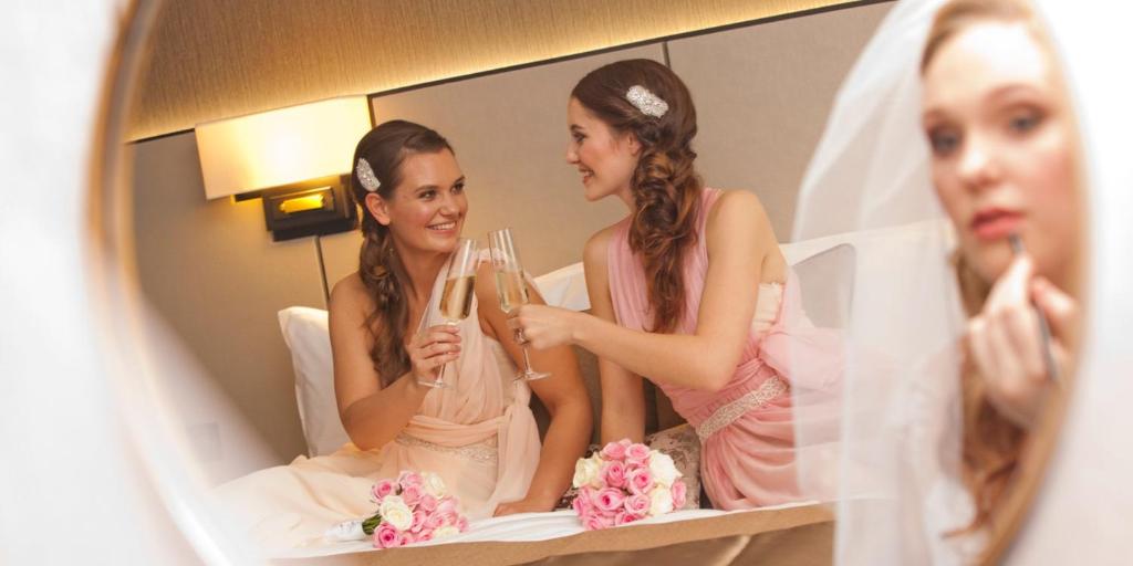a woman holding champagne glasses in front of a mirror at Crowne Plaza Aberdeen Airport by IHG in Dyce
