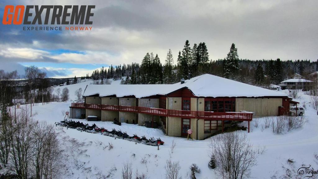 un edificio con un grupo de personas de pie en la nieve en Hattfjelldal Hotell en Hattfjelldal