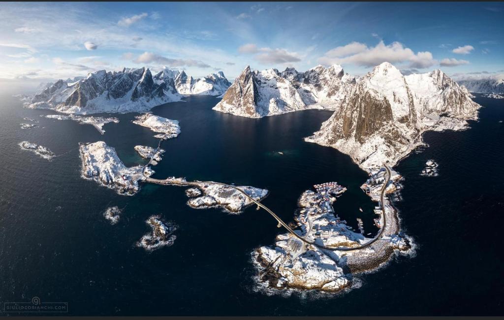 an island in a body of water with snow covered mountains at Reine City Apartment in Reine