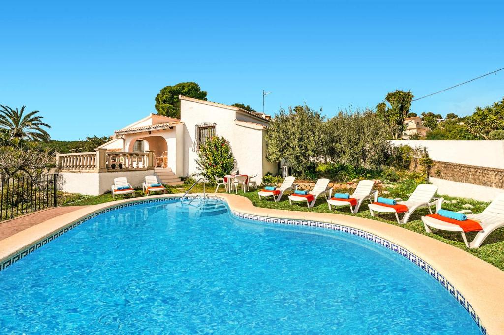 een zwembad met ligstoelen en een huis bij 3060 Villa Elche in Moraira