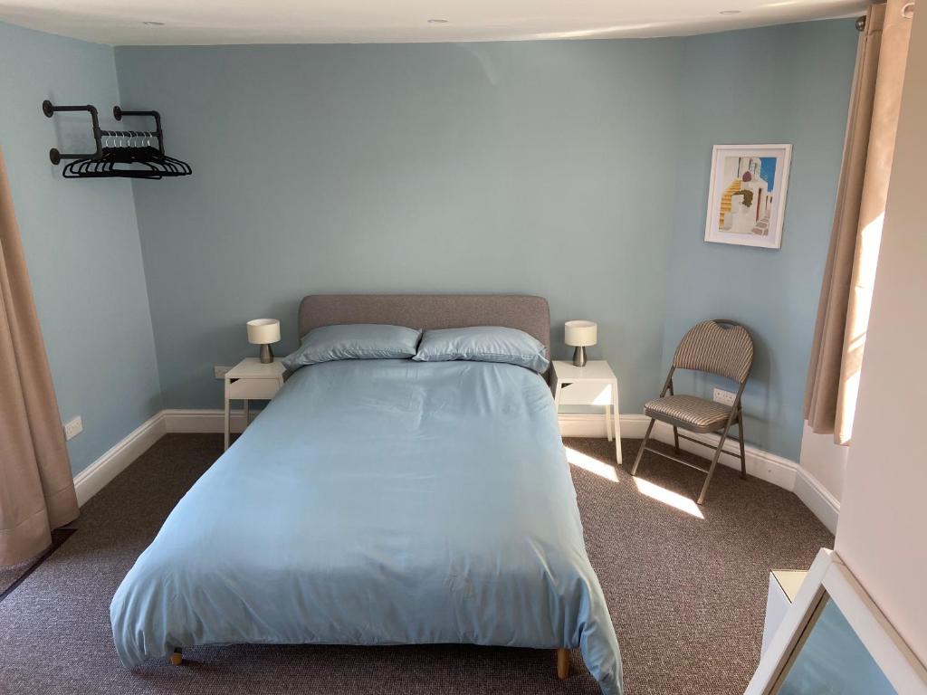 sypialnia z łóżkiem z niebieską pościelą i krzesłem w obiekcie Homewood Airbnb, Combe Martin, Devon - 300m to the Beach! w mieście Combe Martin