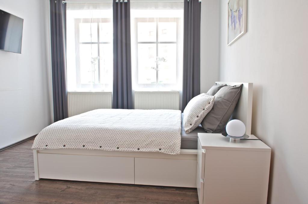 um quarto branco com uma cama e uma janela em R&J apartmány em Broumov
