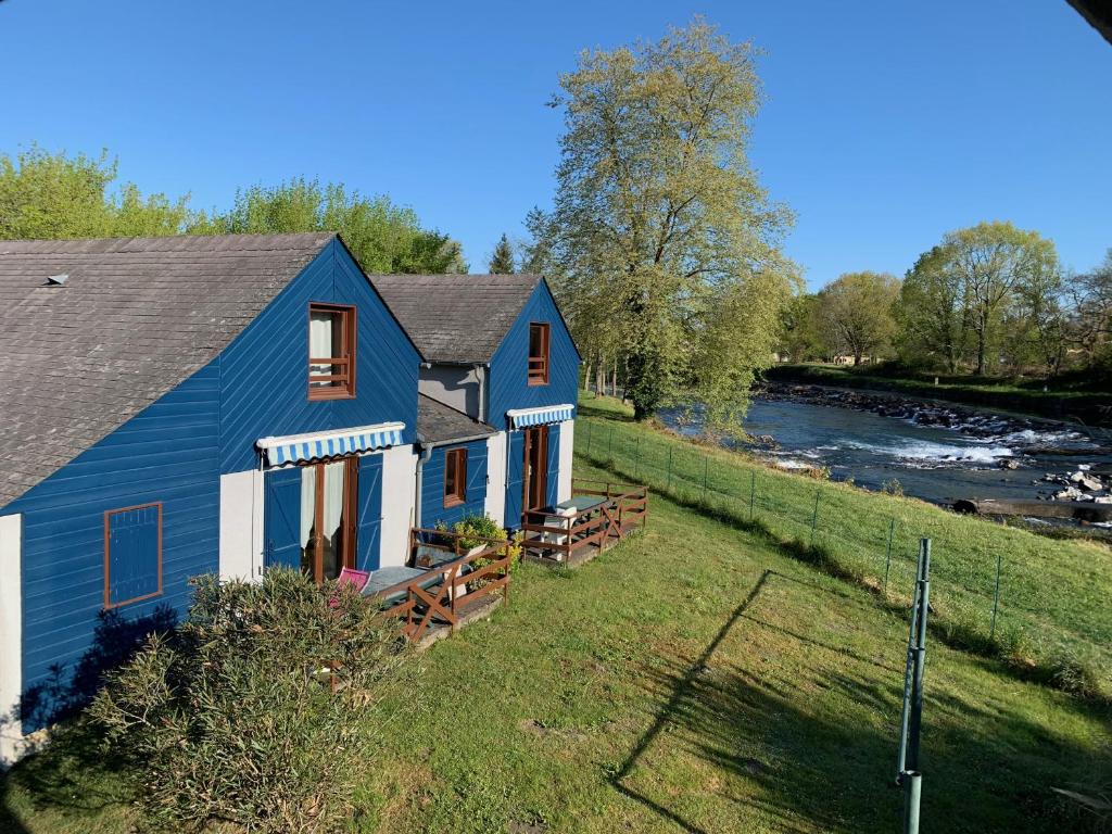 een blauw huis aan de kant van een rivier bij Camping Le Saillet in Lestelle-Bétharram