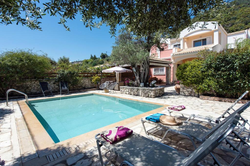 una piscina con 2 sillas y una casa en Villa Palmier, en Ano Pyrgi