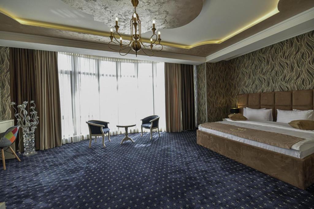 エレバンにあるWelcome Inn Hotelのベッド、テーブル、椅子が備わるホテルルームです。