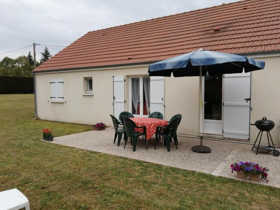 una mesa con sillas y una sombrilla frente a una casa en Maison indépendante en Lailly-en-Val