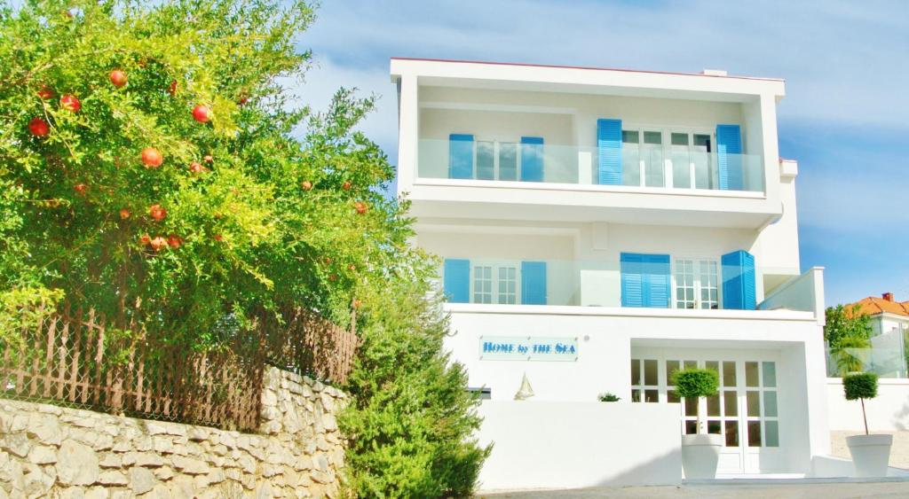Biały budynek z pomarańczowym drzewem przed nim w obiekcie Seaside villa with private pool Home By The Sea - Villa Trogir w Trogirze