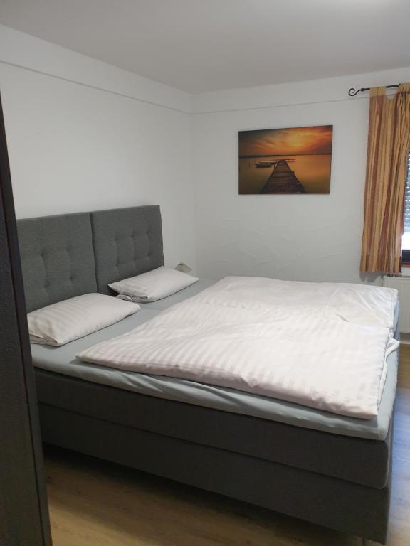 a bedroom with a bed with white sheets and a picture on the wall at Hotel Restaurant Bauernstube in Eschenburg