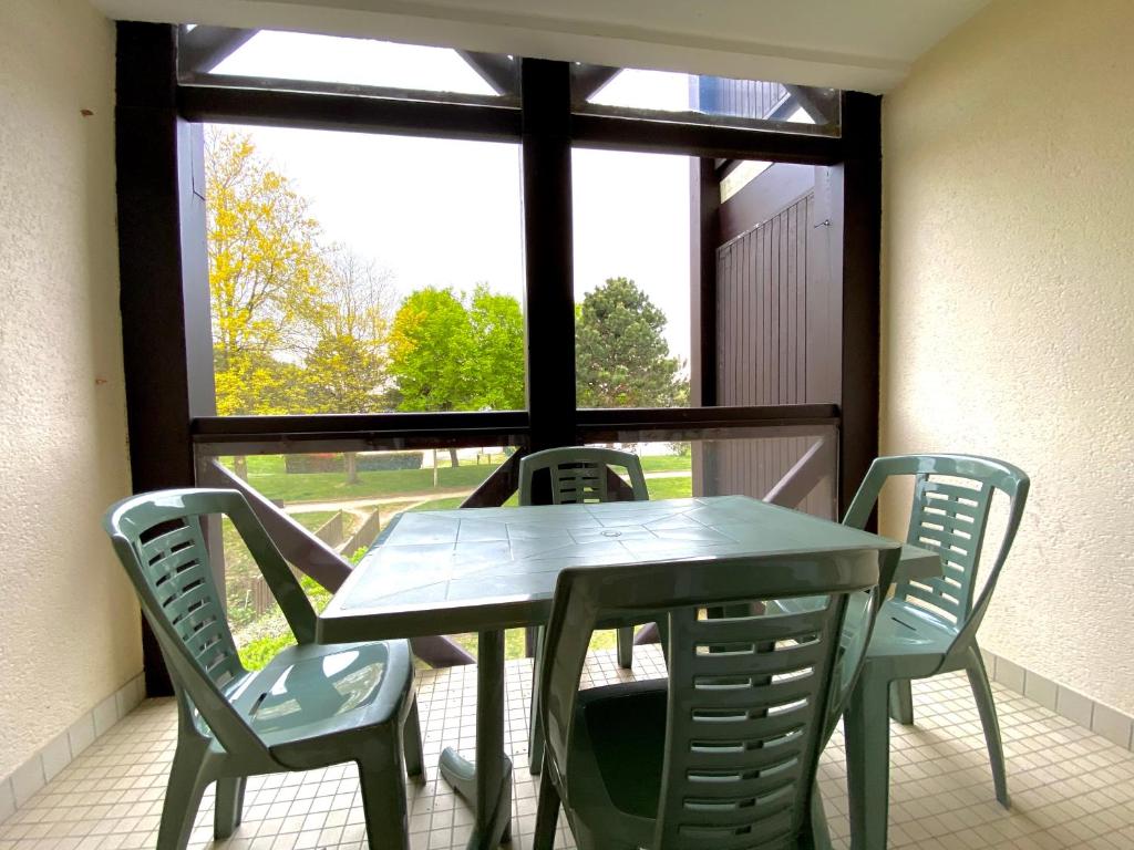 une table et des chaises dans une pièce avec une fenêtre dans l'établissement REF 042 Appartement T2 avec balcon et piscine Arzon, à Arzon