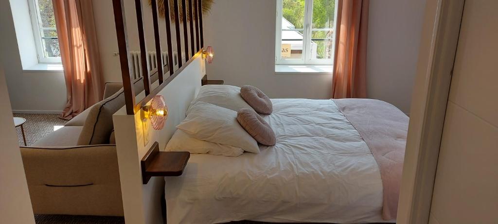 a bedroom with a bed with white sheets and pillows at auberge le petit mas in Issoire