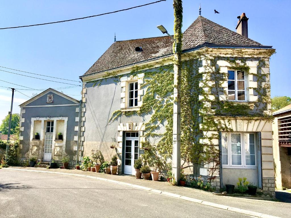 una casa vieja con hiedra al lado de una calle en La Maison Haute, en La Fosse-de-Tigné