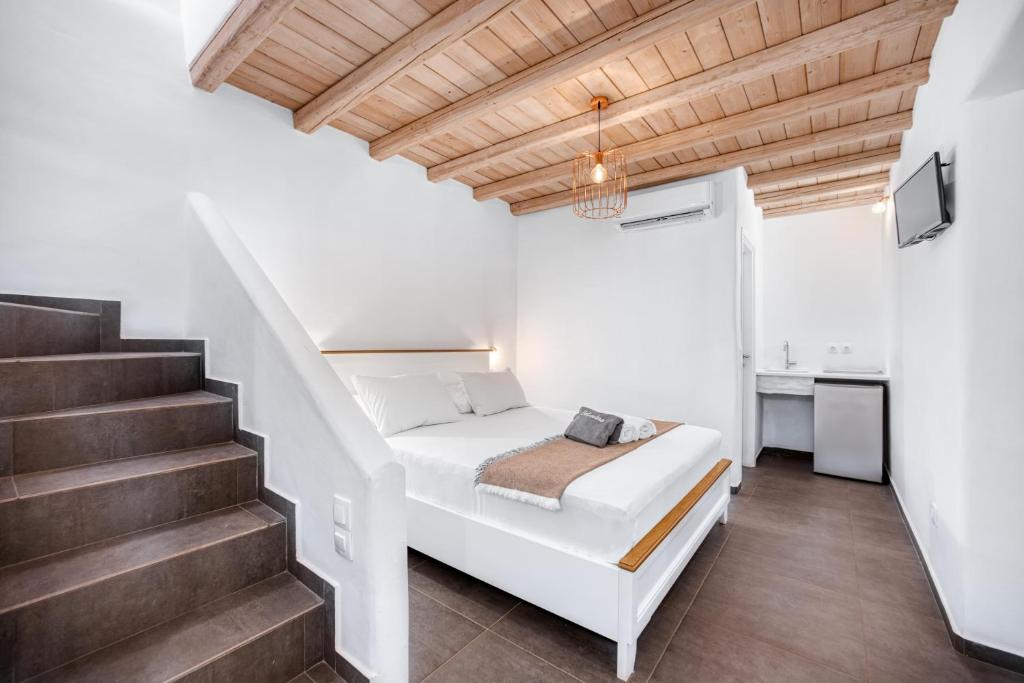 a white bedroom with a bed and stairs at Belvedere in Livadi