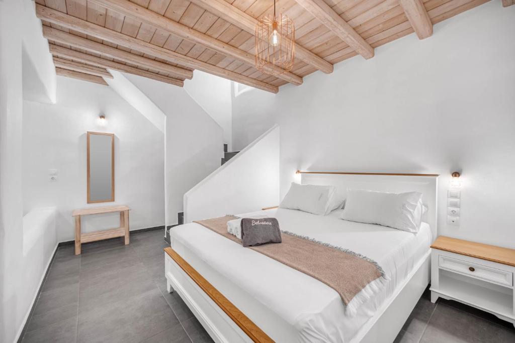a white bedroom with a white bed and a wooden ceiling at Belvedere in Livadi