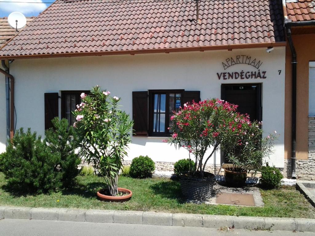 ein Haus mit zwei Bäumen und Blumen davor in der Unterkunft Gyöngyvendégház in Szigetvár