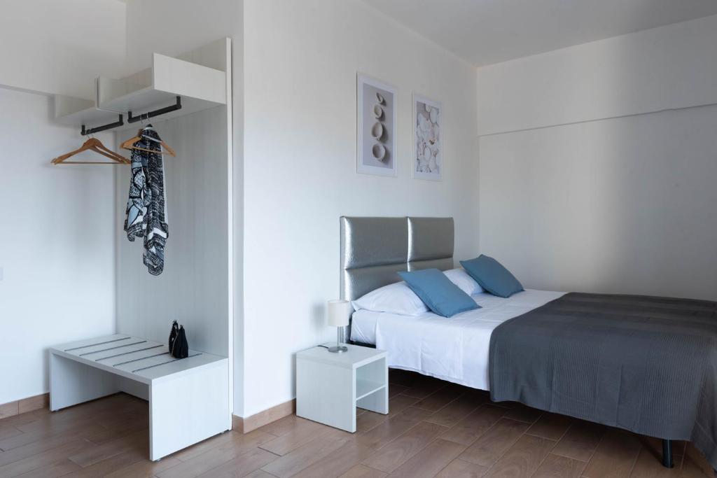 a white bedroom with a bed with blue pillows at B&B Sirentum in Sorrento