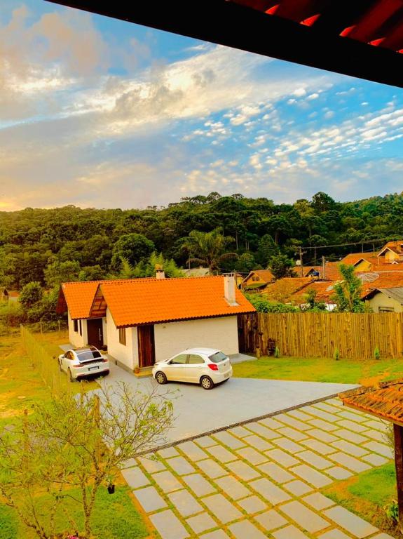 a house with two cars parked in a parking lot at Chalé Villa Magrini in Monte Verde