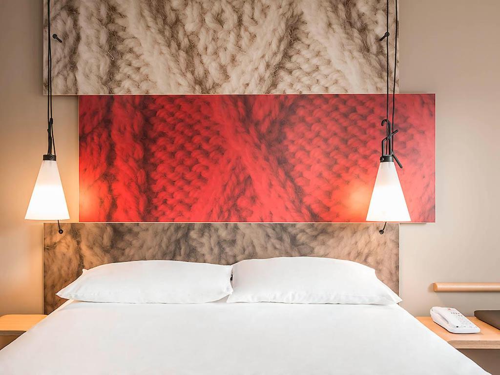 a bedroom with a white bed with two lights above it at Ibis Saint Étienne - La Terrasse in Saint-Étienne