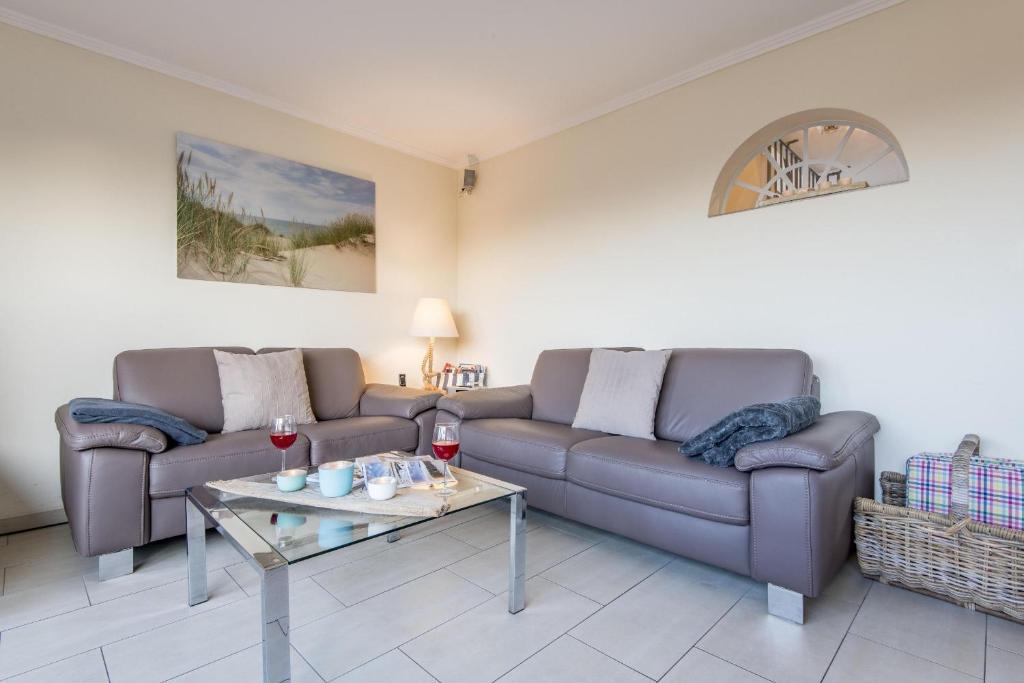 a living room with two couches and a table at Heidehueschen in Braderup