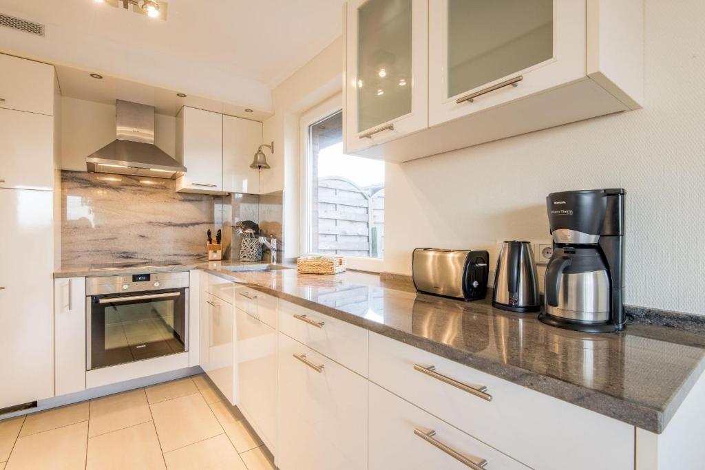 Heidehueschen في Braderup: مطبخ مع دواليب بيضاء وصانع قهوة على الكاونتر