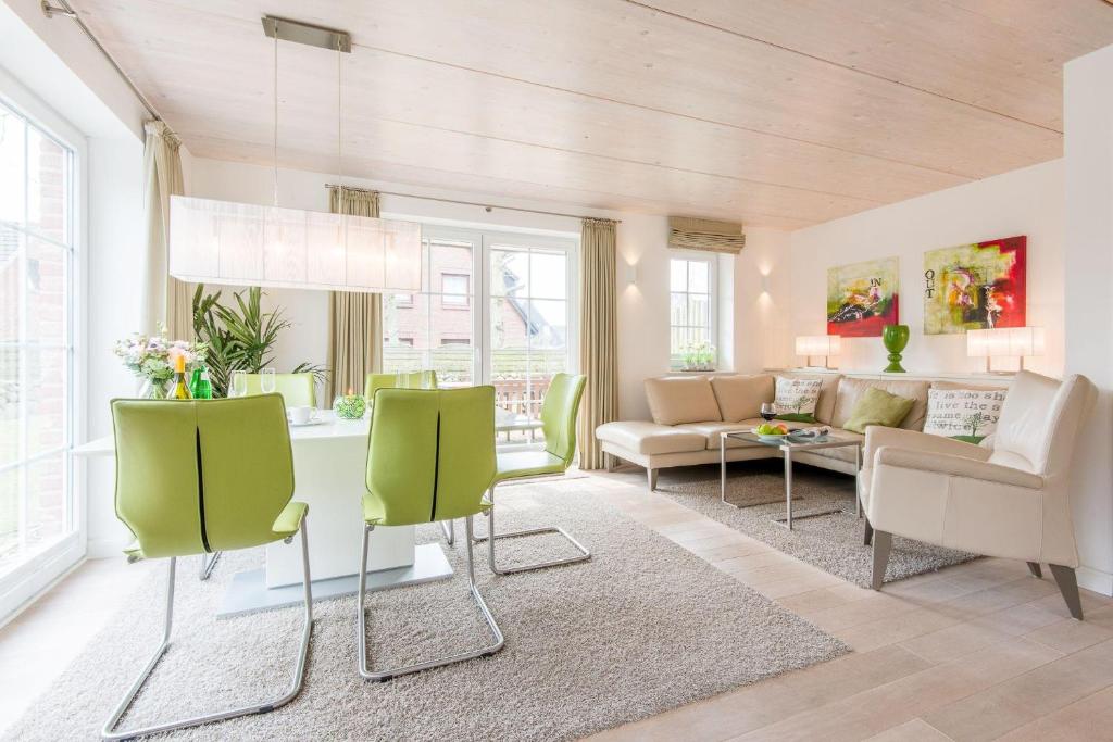 uma sala de estar com uma mesa e cadeiras verdes em Haus Nordgang 8 Haushaelfte B em Westerland