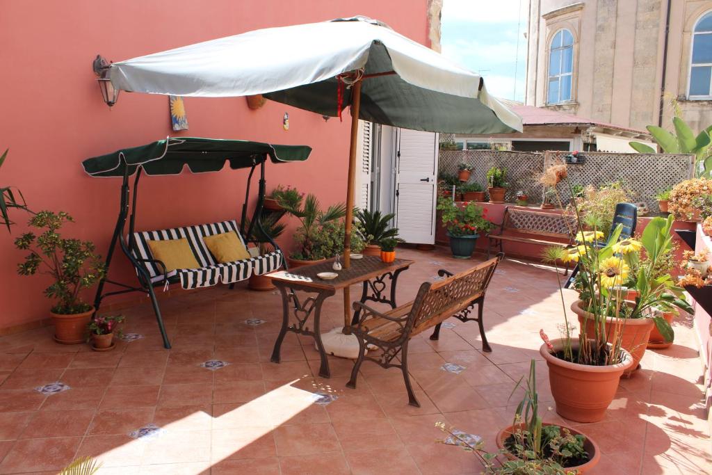 un patio con sombrilla, mesa y sillas en L'Isola Di Ortigia, en Siracusa