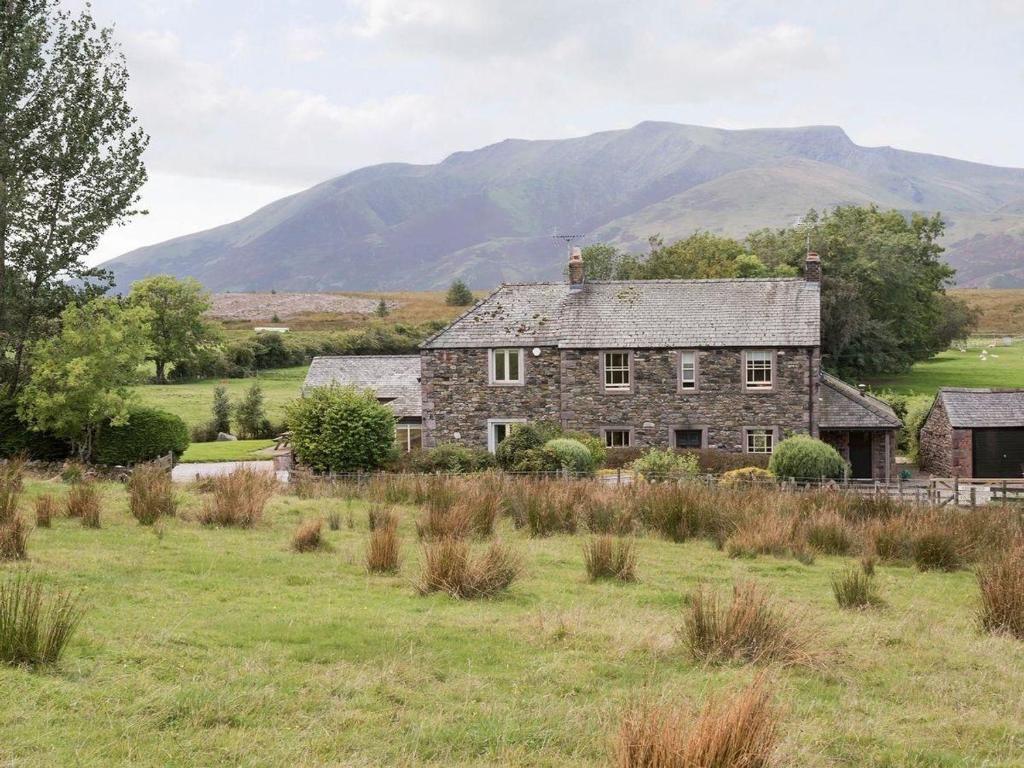 an old stone house in a field with mountains in the background at Beckwood in Penrith