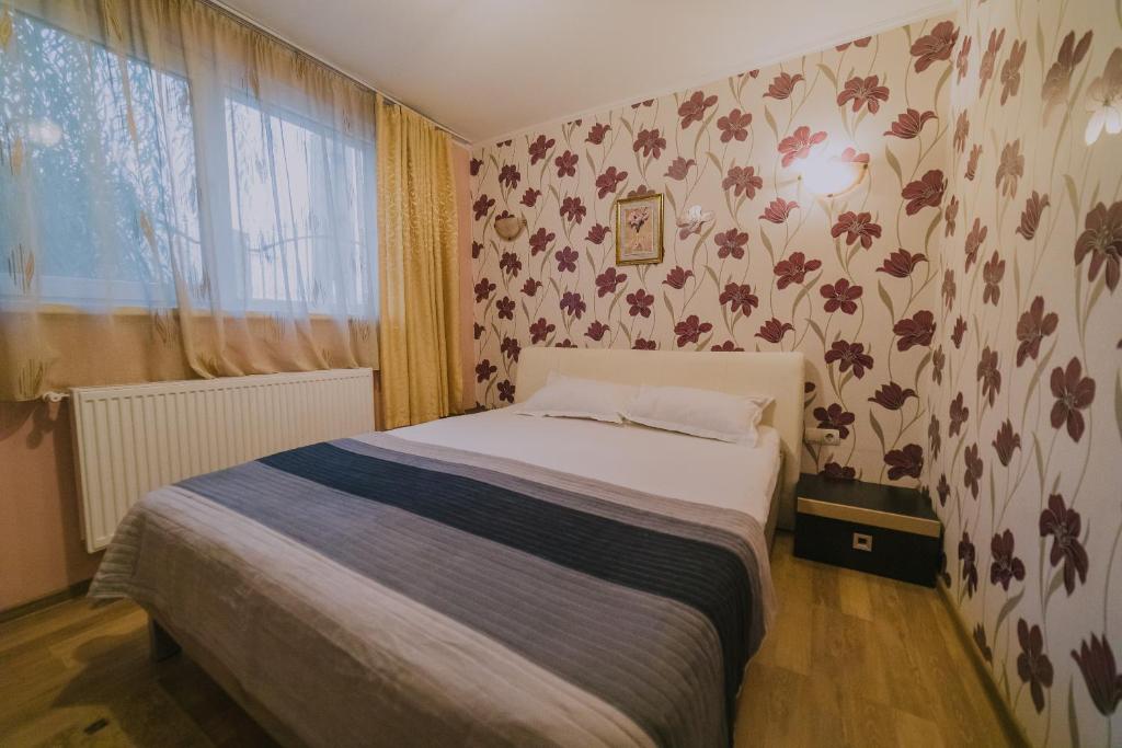 um quarto com uma cama e um papel de parede florido em Hostel Denisa em Buzau