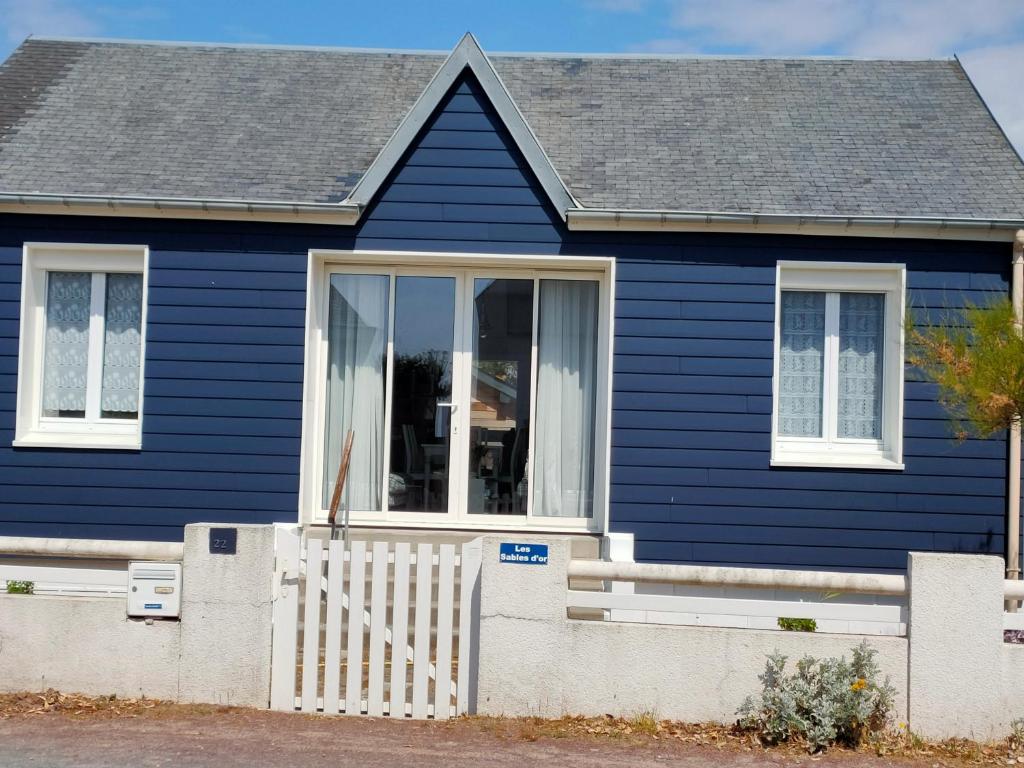 ein blaues Haus mit einem weißen Zaun in der Unterkunft Les sables d'or in Agon Coutainville