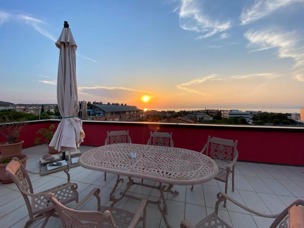 un patio con mesa, sillas y puesta de sol en Apartments Apolon Izola, en Izola