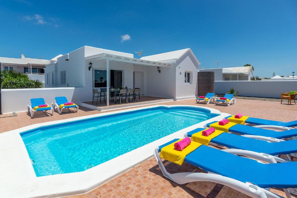 a swimming pool with chairs and a house at Villa Cancela by Villa Plus in Puerto del Carmen