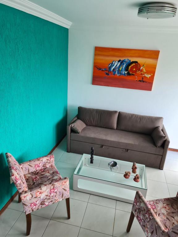 ein Wohnzimmer mit einem Sofa und 2 Stühlen in der Unterkunft Lindo Village na Praia de Stellamaris in Salvador