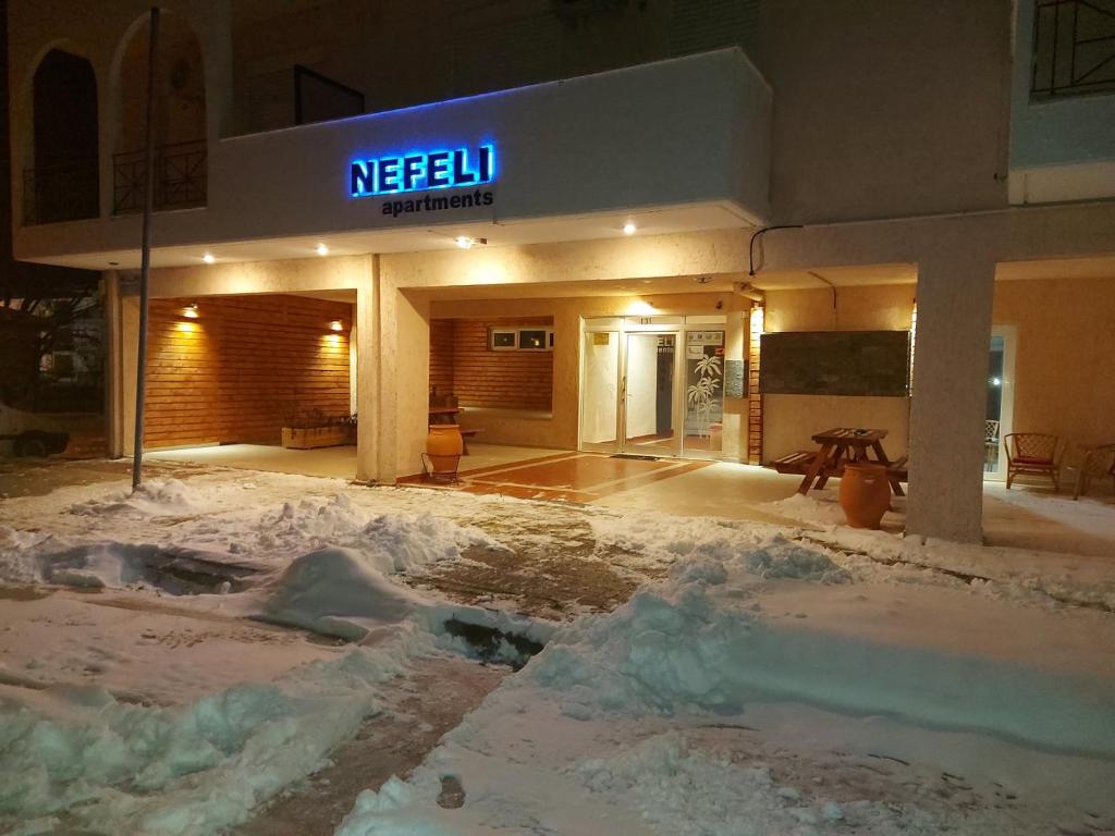 un edificio con nieve en el suelo delante de él en Nefeli Apartments Ορεστιάδα, en Orestiada