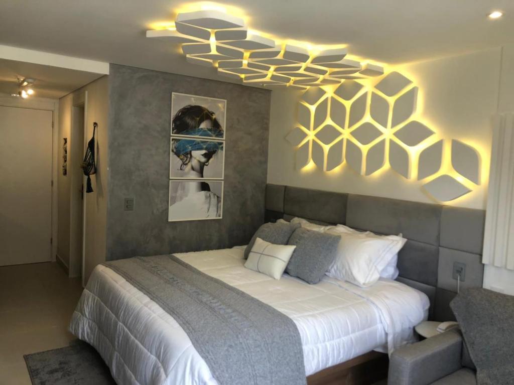 um quarto com uma cama com uma pintura de favo de mel na parede em Flat Garden Itaipava em Itaipava